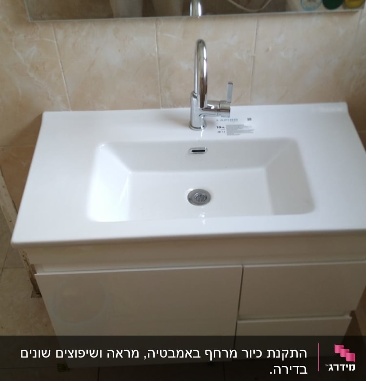 כיור לבן עם ברז כרום מותקן על ארון אמבטיה